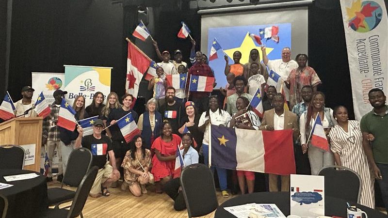 CFA Chaleur members and newcomers waving Acadian flags at a community gathering