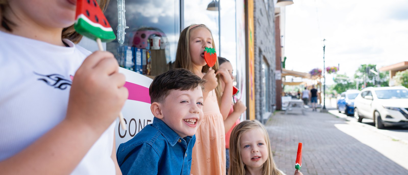 Kids with candy lollipops on the sidewalk outside a downtown Bathurst shop