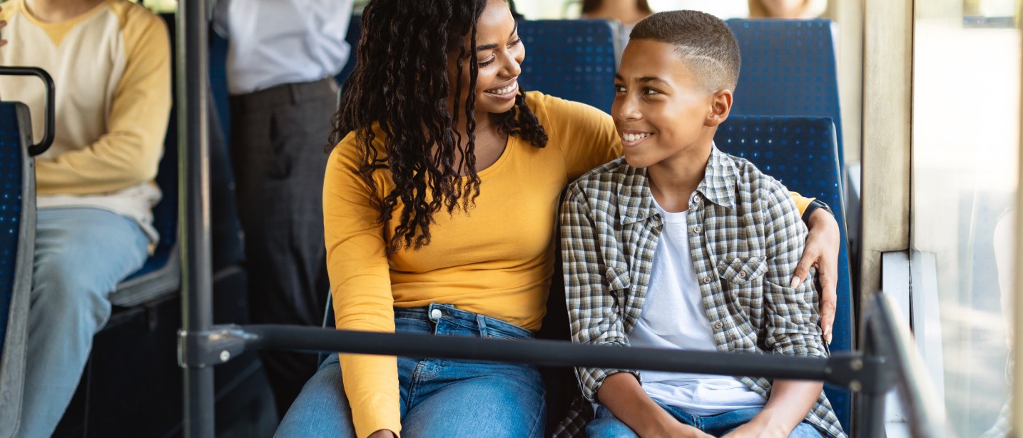 A mother and her son sharing a seat on the bus